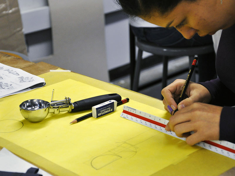 Woman drafts a sketch of an ice cream scoop mechanism for a Design Bloc course.
